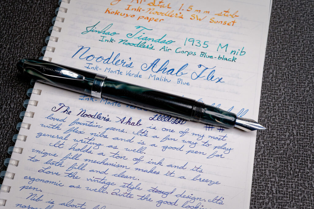 A photo of the Noodler's Ahab flex fountain pen on top of a notebook with writing samples showing how it writes.